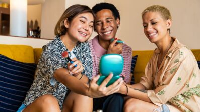 Group of LGBTQ+ young people on a sofa putting on makeup