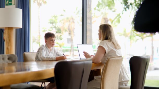 Support worker with laptop sat across the table from young person